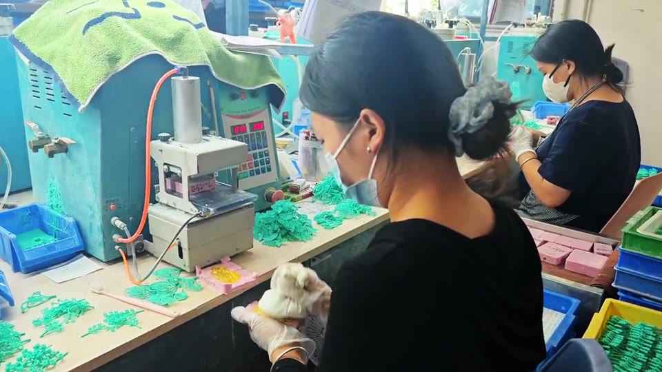 A worker handling components at a jewelry workstation.